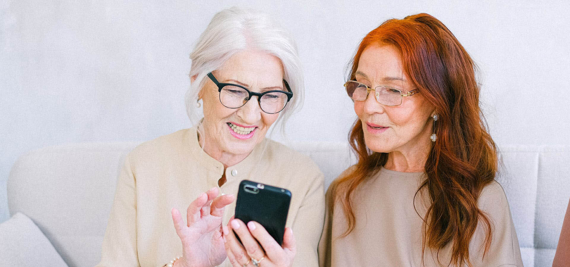 To damer som ser på skjermen til en mobiltelefon